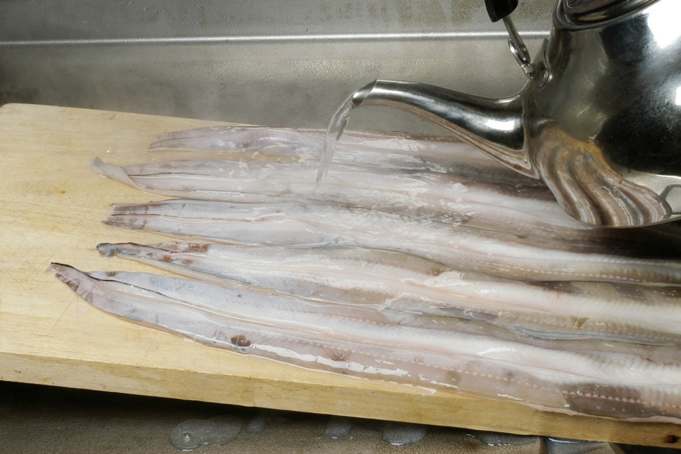 佃煮や煮アナゴの場合は、傾けたまな板に皮を上にして並べ、熱湯を手早く回したら……