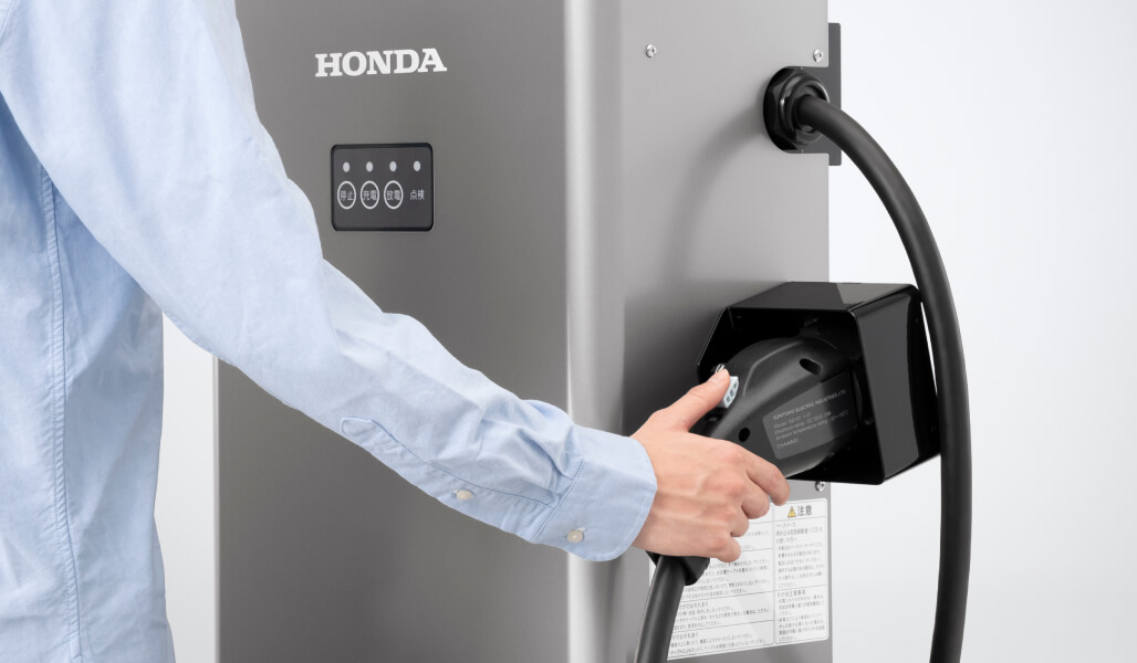 Honda V2H Standから充放電コネクターとケーブルをコネクターホルダーから取り外す画像。