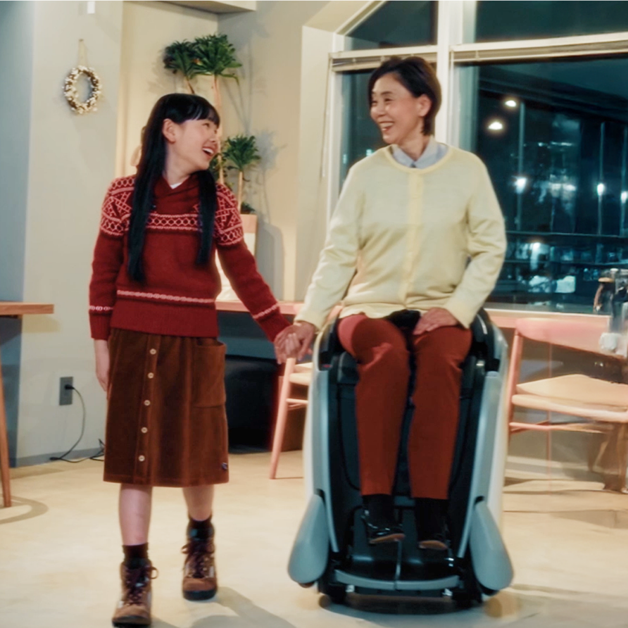 室内でUNI-ONEに乗りながら、隣を歩く人と手をつないで移動する様子