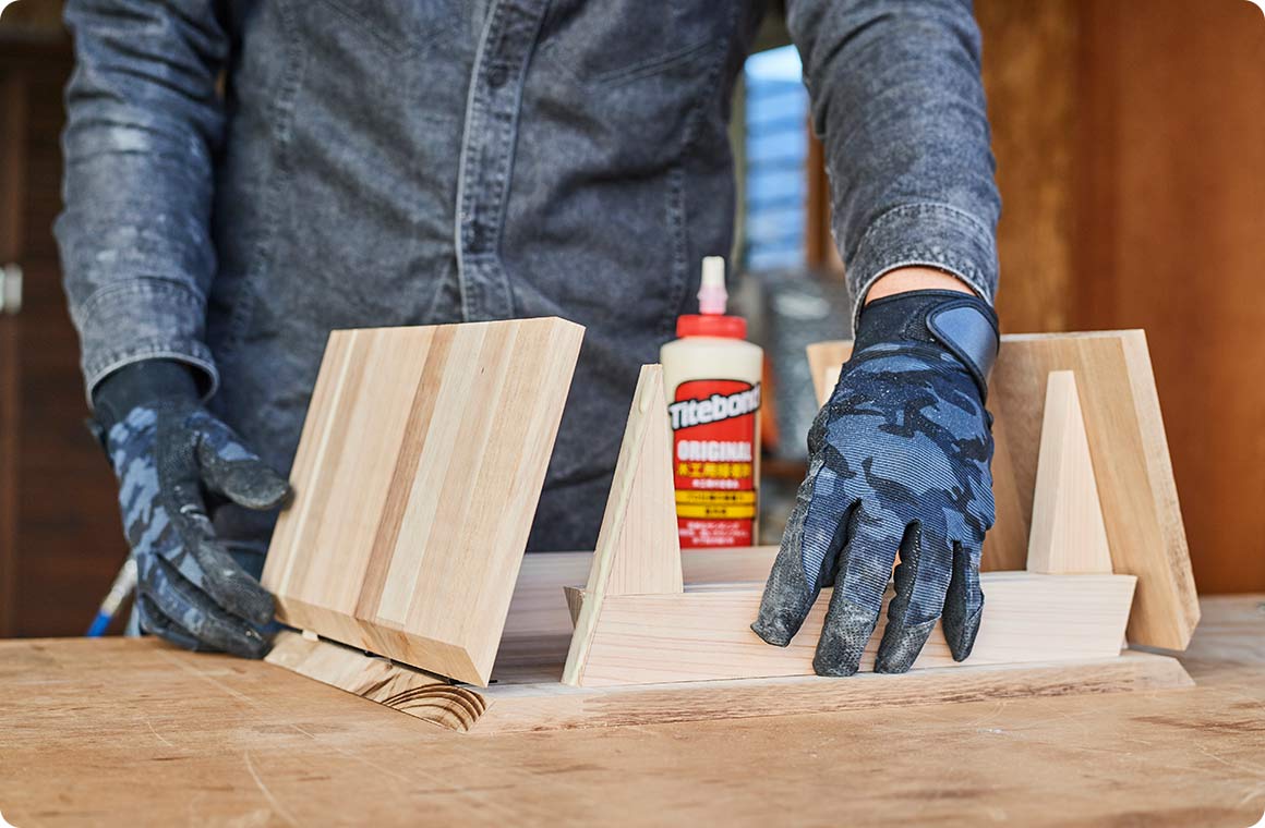 脚側に木工用ボンドを塗布し、蝶番から外へ15mm離して左右の天板の裏側に固定する