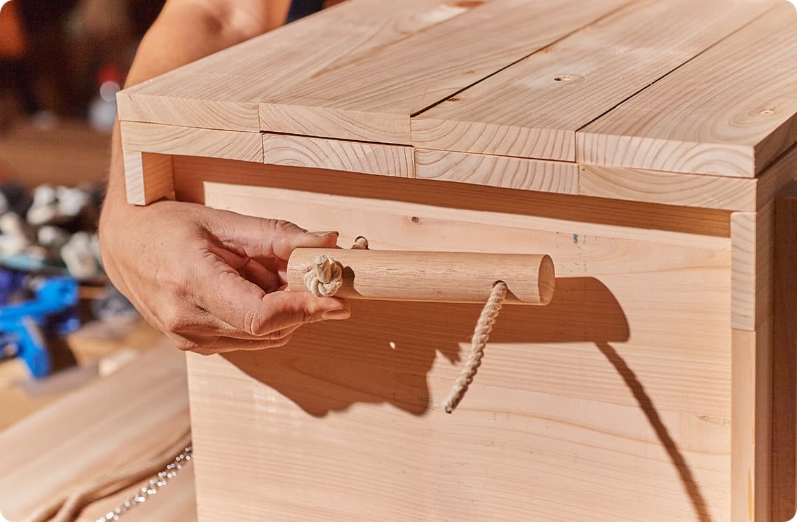 取っ手用の丸棒Hに穴を開け、ロープを側板③と丸棒Hに通したら、先端を結んで固定する