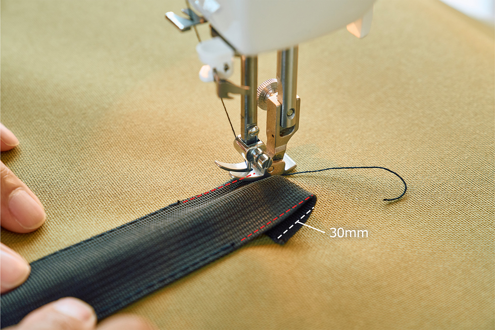 テープの先を内側に30mm折り、縫い合わせる