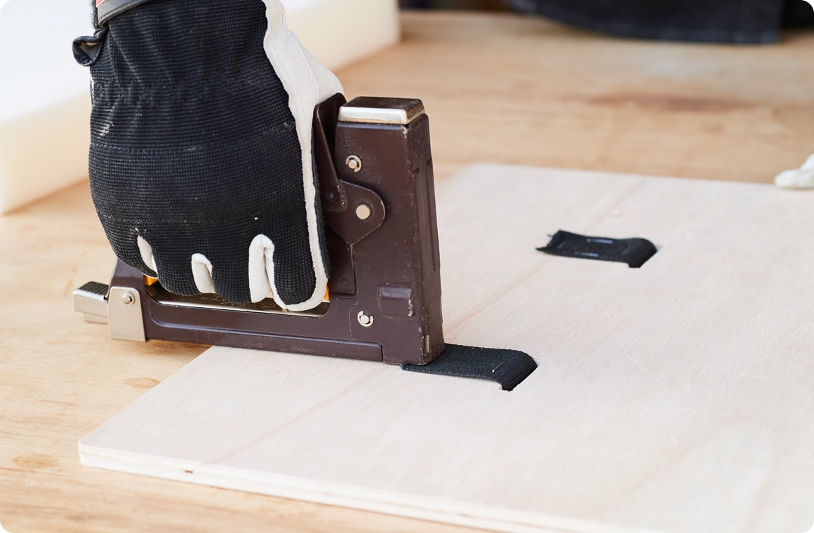 Fのホゾ穴にナイロンテープを通し、ウレタンクッション面側に50mm出してガンタッカで固定