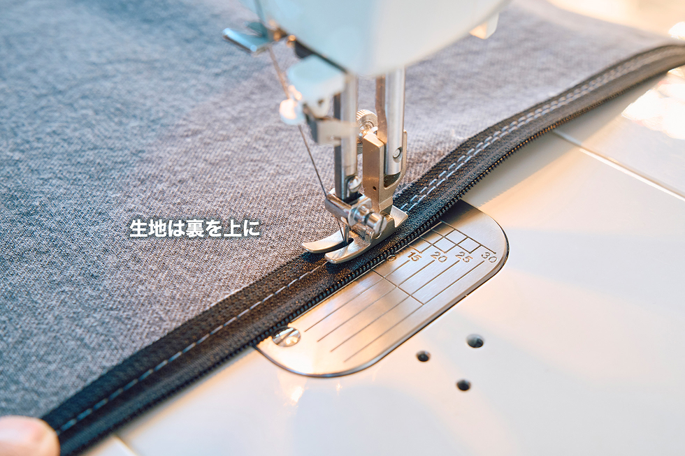 生地は裏面を上にして、ジッパーの先ほど縫った内側（生地側）を縫い付ける