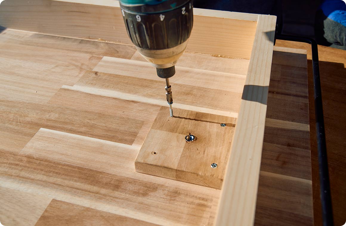 止めネジアダプターを取り付けた脚受け補強板B-4を、スライドテーブルの天板B-1の内側にビスで固定する。