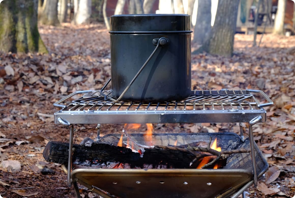 沸騰したら、鍋を置いている台の高さを上げるか、薪をならして鍋底に炎が当たる程度にします。この状態で12～15分火にかけます。バーナーの場合は、沸騰後2分ほど強火、その後はとろ火で12～15分加熱します。