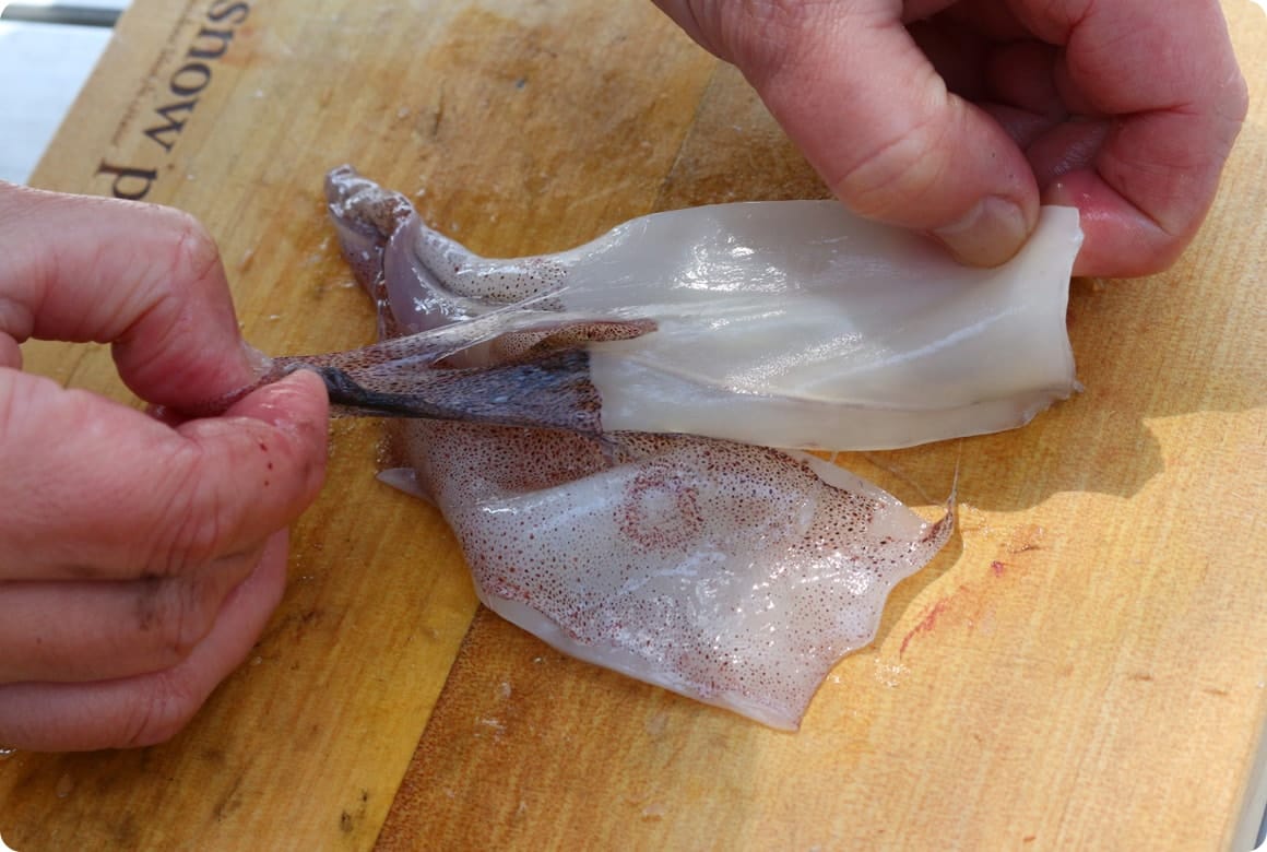 残った軟骨と皮をむき取ります。皮むきはエンペラ側からが定石ですが、むきやすい方向から引っ張って大丈夫です。指先ではうまく皮がとれない場合は、キッチンペーパーを使うとすべりにくくなり、むきやすくなります。 最後に胴とゲソを流水で洗い流して下処理は終了です。