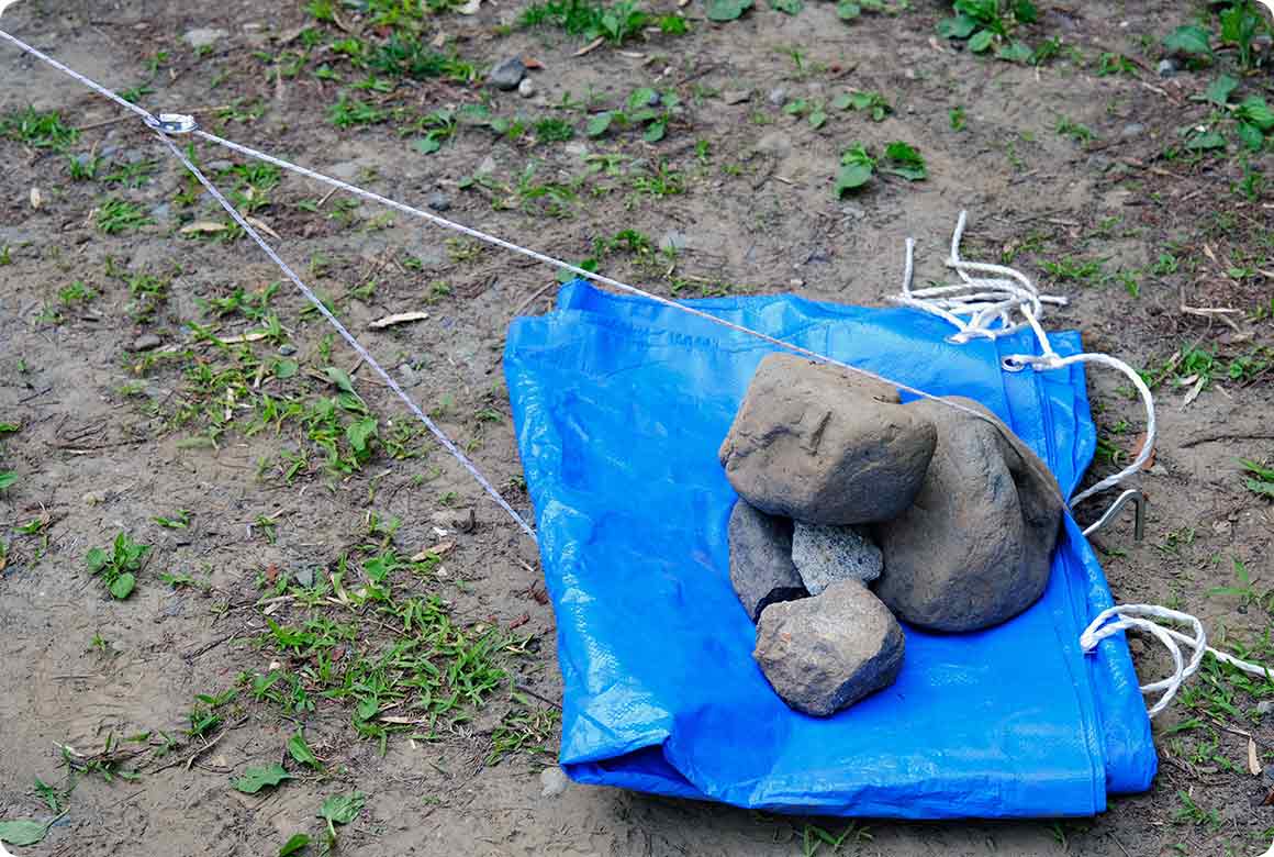 大きめの石があればいいのですが、小さめの石しかない場合はブルーシートに石を積み重ねて対応します。