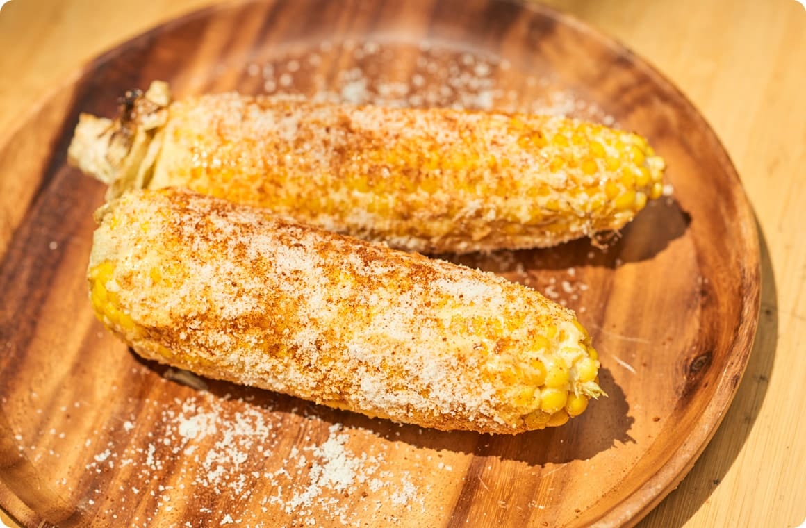 とうもろこしに粉チーズを振りかけて盛り付けた画像