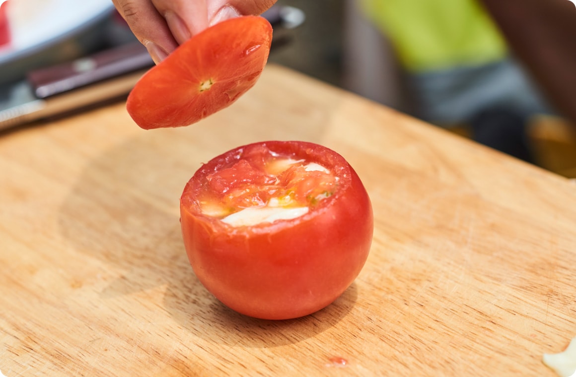 くり抜いたトマトにチーズを入れ、カットしたトマトで蓋をする画像