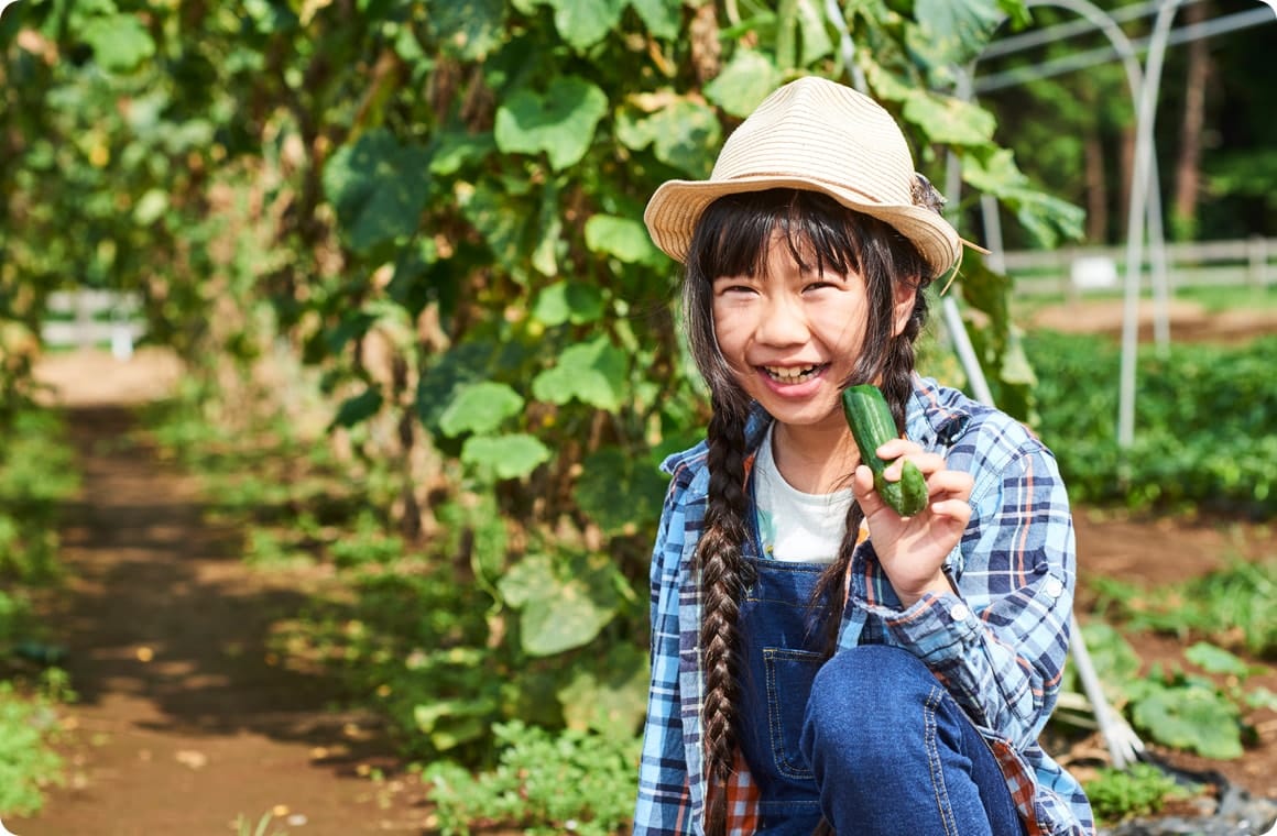 きゅうりをかじって笑う子供の画像