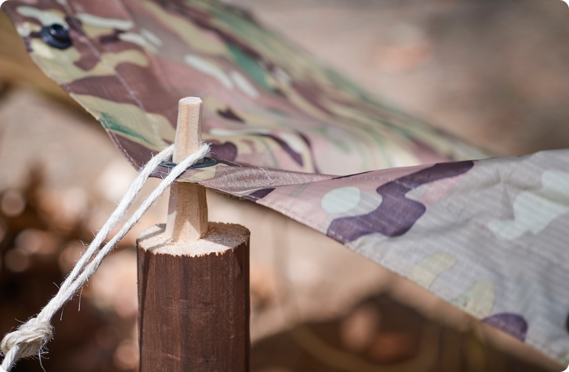 ポールの先端をポンチョのグロメットに通し、麻紐を引っ掛ける画像