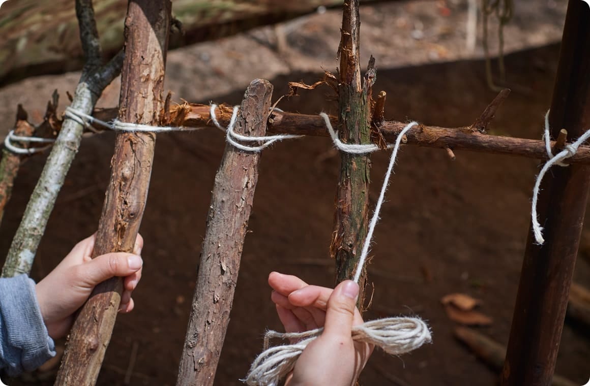 枝に枝を立てかけて、麻ひもで固定していく画像