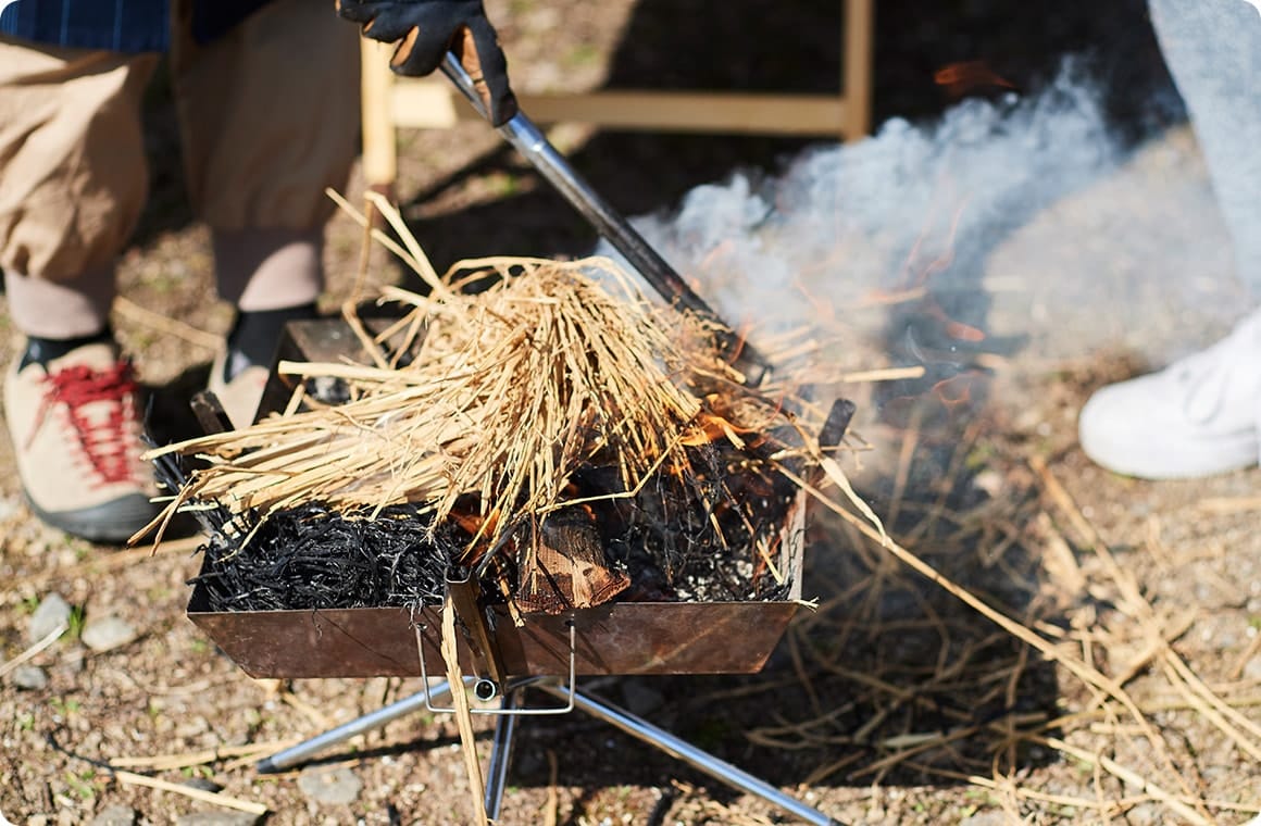 焚き火に藁を入れる画像