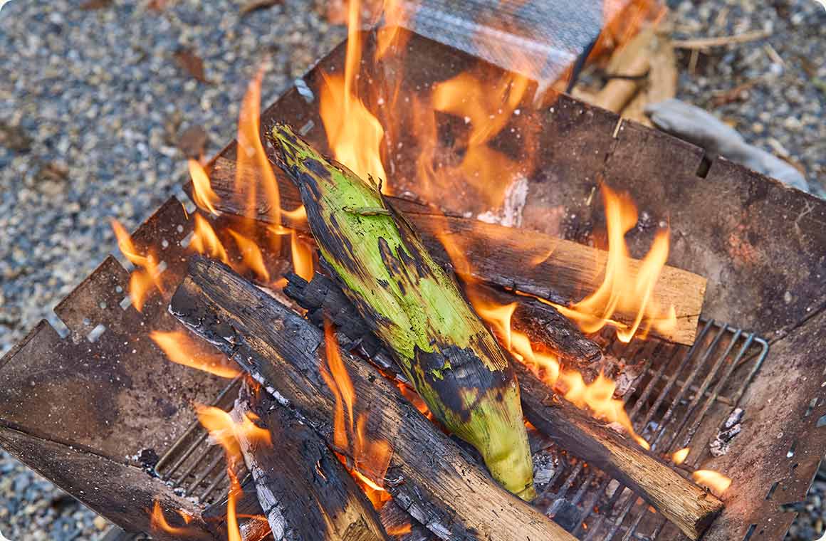 皮付きのまま直火で焼いたとうもろこしの画像