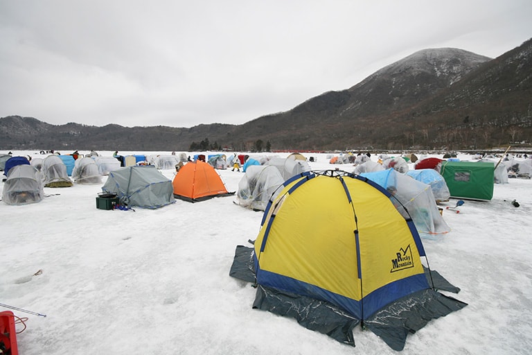 真冬の風物詩、氷上の穴釣り。思い思いのポイントにドリルで穴を開け、テントで暖を取りながらねらう