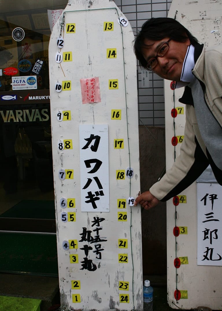 船の釣り座は先着順に選ぶ。写真のようなボードにプレートを掛けたり、直接船に荷物を置くなど方法はさまざま。船首（ミヨシ）や船尾（トモ）は広範囲を探れる反面、揺れやすい。慣れないうちは船酔いしにくい中央付近（胴の間）を選んでもいいだろう