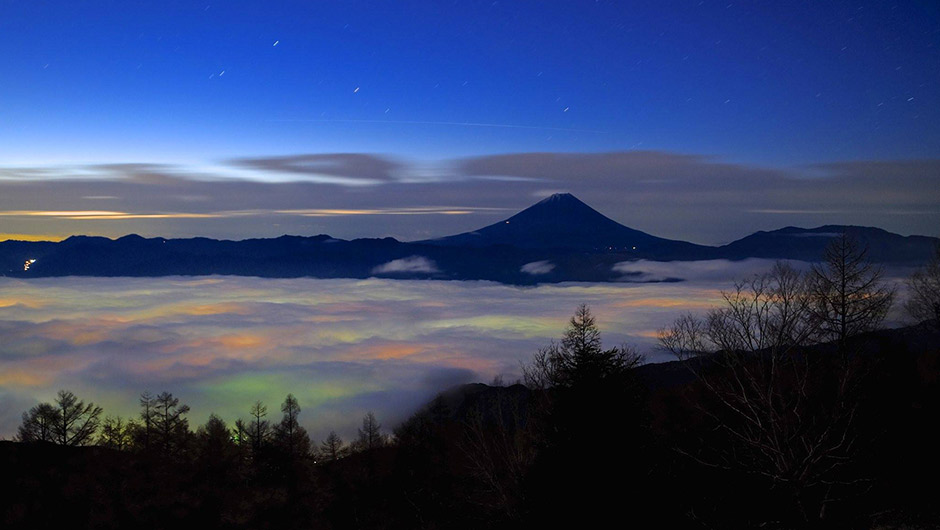 街のネオンがうかび上がる雲海