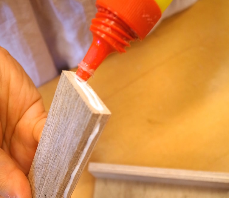 側面用の板にボンドをつけ、	仮(かり)組みのときと同じように組み立てて輪ゴムで固定し、はりつける。