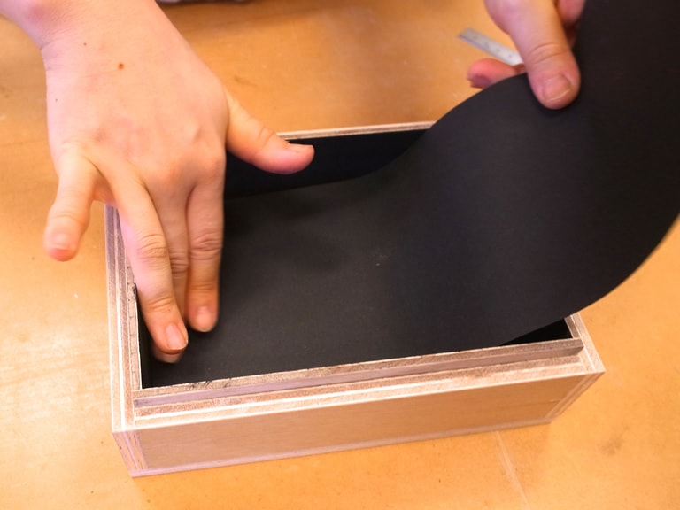 印画紙が取り出しやすくなるように、黒い画用紙を半分に折ってベロをつくり、左右に両面テープをはって箱本体の内部にしっかり固定する。