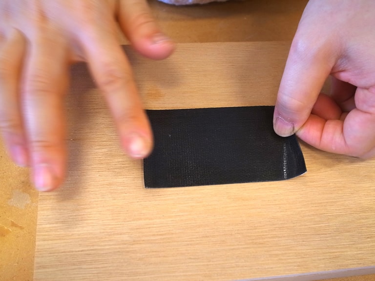 黒いガムテープよりも一回り小さい黒い画用紙をガムテープにはり、フタの外側から穴（あな）をふさぐようにはりつける。※写真をとるときに外すので、外しやすいようにテープのはしを内側に折りこんでおこう。