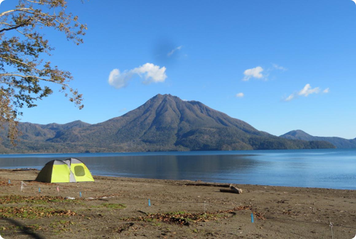 キャンプサイトから望む恵庭岳。透き通った支笏湖の湖畔沿いにテントを設営できる
