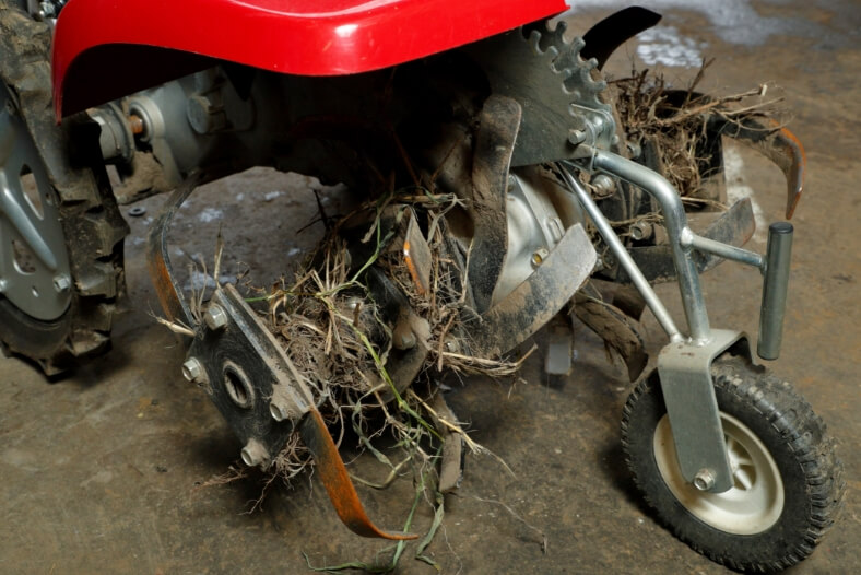耕うん爪を外し清掃する。車軸に草や根が絡まると故障を誘発するので注意。