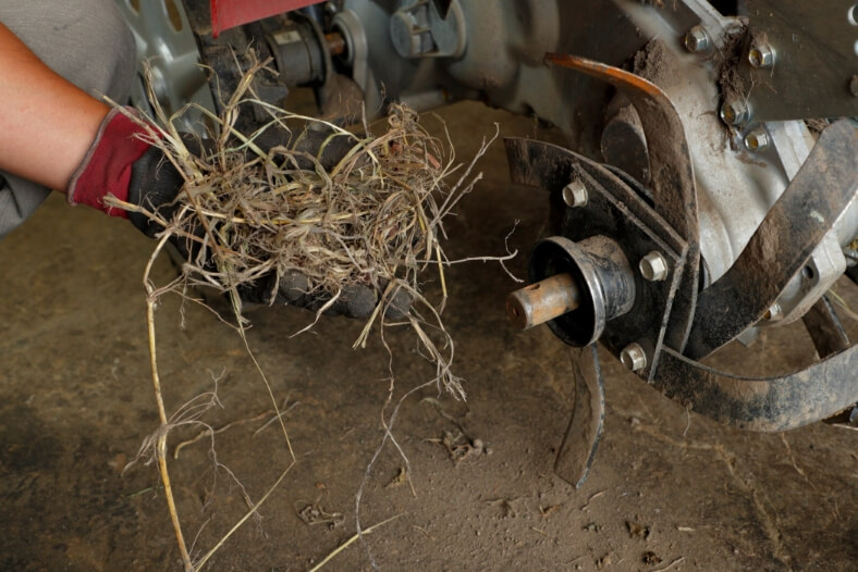 耕うん爪を外し清掃する。車軸に草や根が絡まると故障を誘発するので注意。